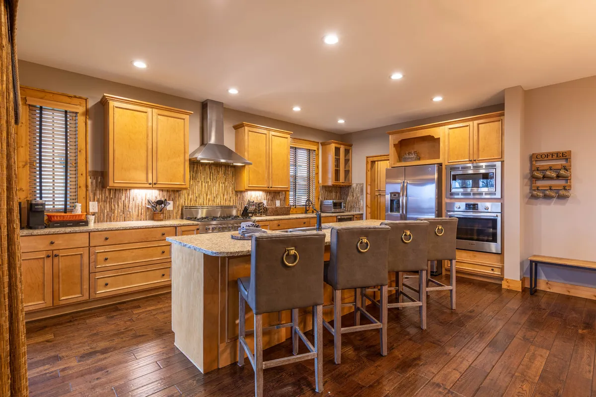 Set in the kitchen, this image highlights a kitchen island with stools, surrounding cabinets, and modern appliances. The space is well-organized for cooking and storage, suggesting ample room for groceries and meal prep.