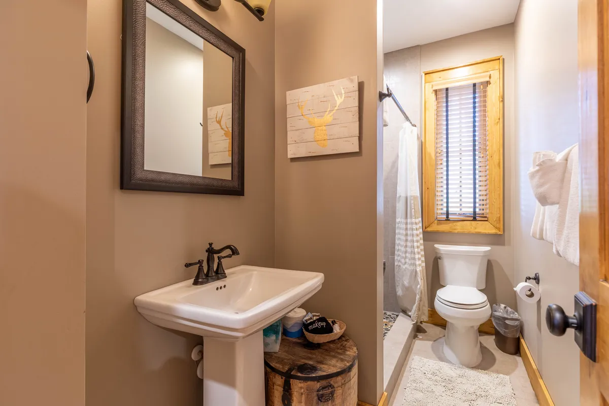 A tranquil bathroom with a sink, shower, toilet, and wooden accents, offering a comfortable setting for refreshment and relaxation after a day outdoors.