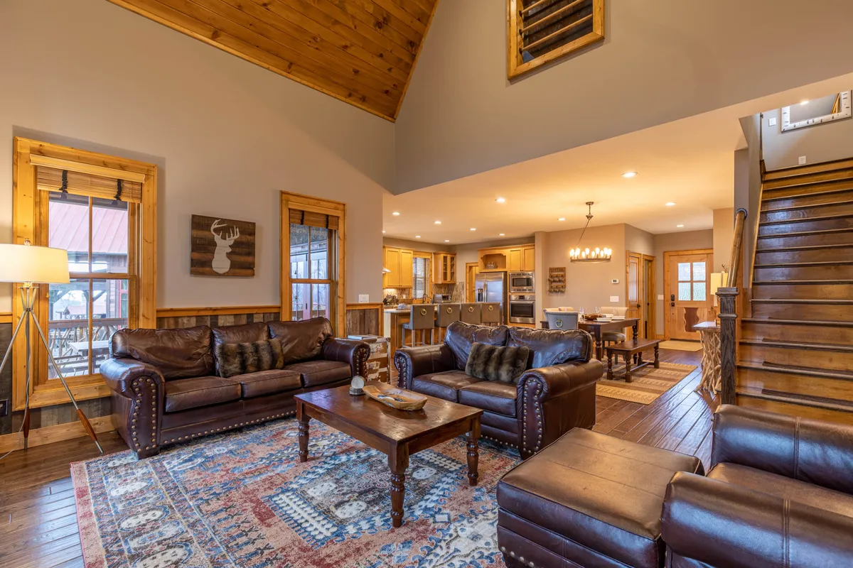 A cozy interior living area featuring leather sofas, a wooden coffee table, and a staircase leading up. The space is designed for relaxation and gathering after a day of activity, with elements that suggest comfort and togetherness.