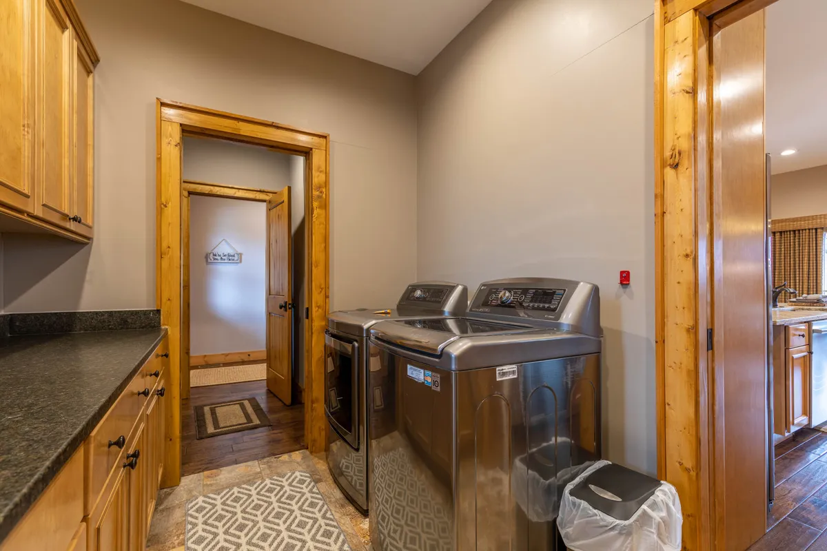 This image centers on a laundry area featuring washing machines, a kitchen door, and a rug, with a practical yet warm ambiance. The space is bright and organized, reflecting convenience and ease of use for guests.